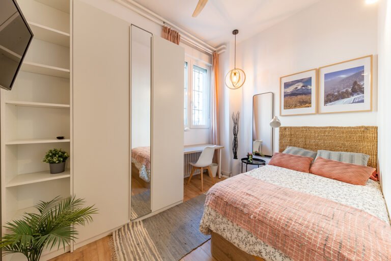 Dormitorio reformado con cama doble, estanterías y escritorio
