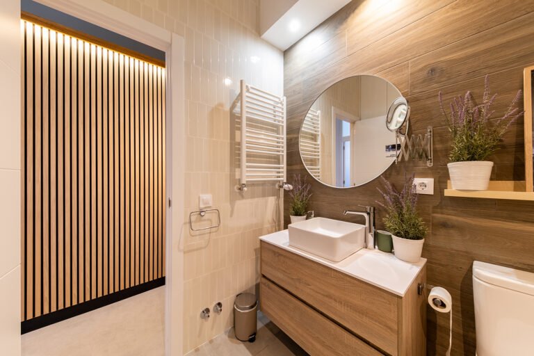 Baño reformado con lavabo de madera y espejo redondo